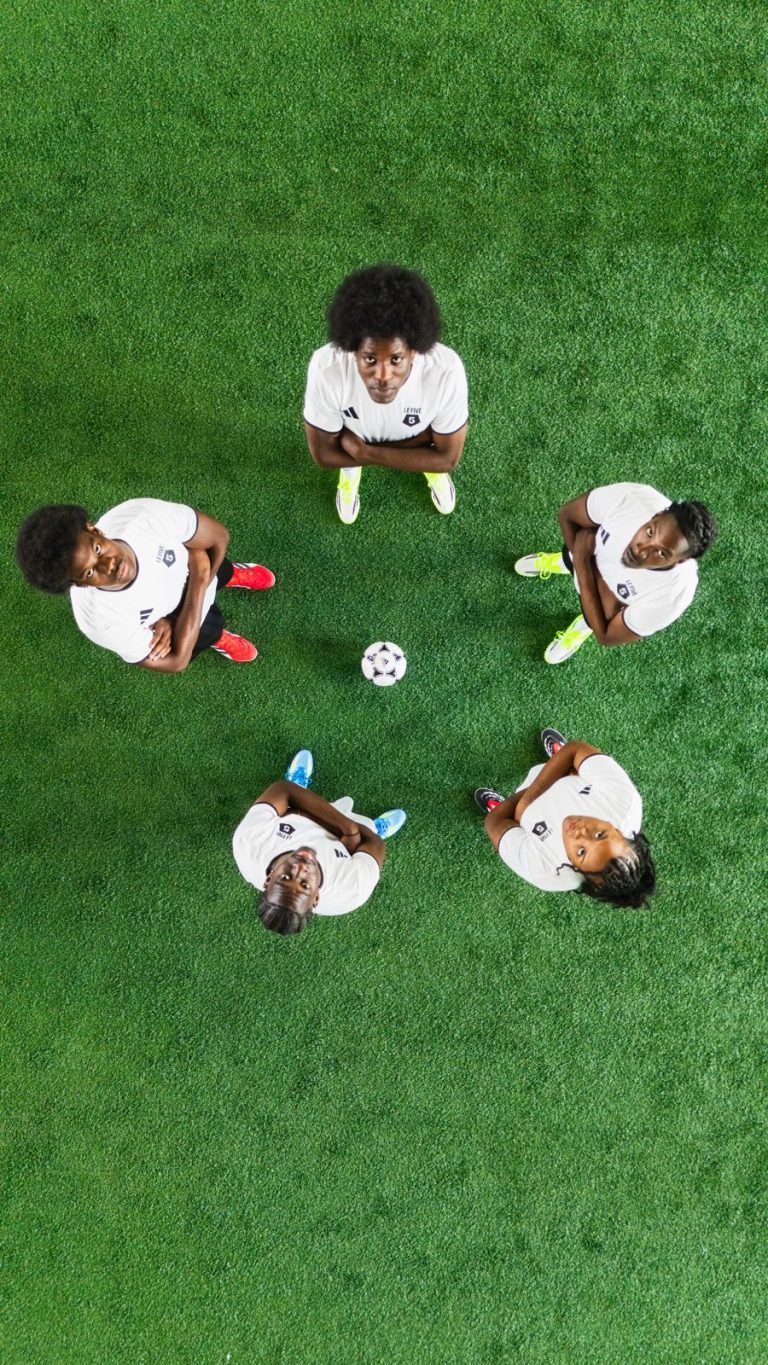 Joueurs de foot allongés en cercle autour d’un ballon, vus du dessus