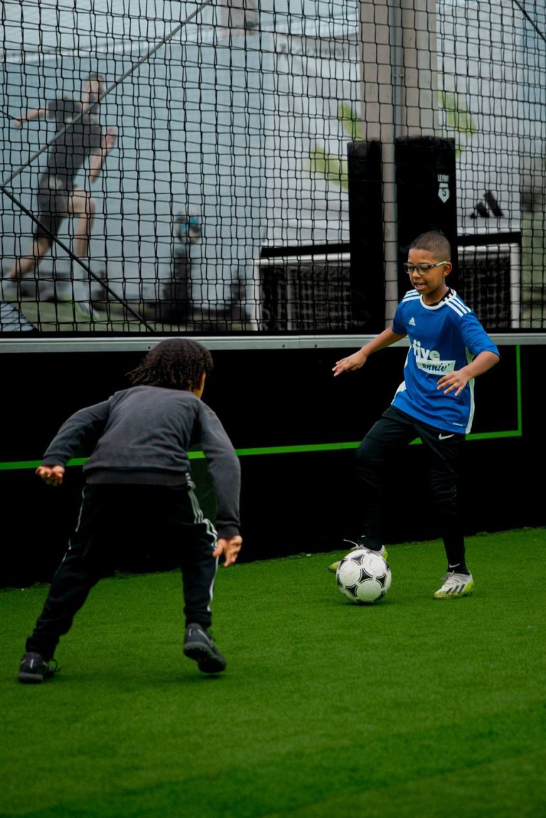 Enfant qui frappe le ballon sur un terrain de foot à 5